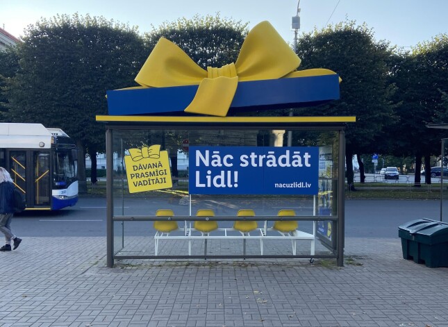 Reklāma sabiedriskā transporta pieturā pie Katedrāles.
