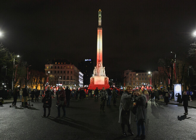 FOTO: cilvēki tver svētku sajūtu pie patriotiskās krāsās mirdzošā Brīvības pieminekļa