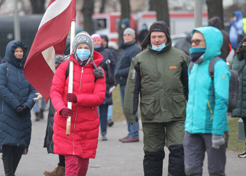 Sanākušie ir dažāda vecuma cilvēki, rokās dažiem ir Latvijas karogi.