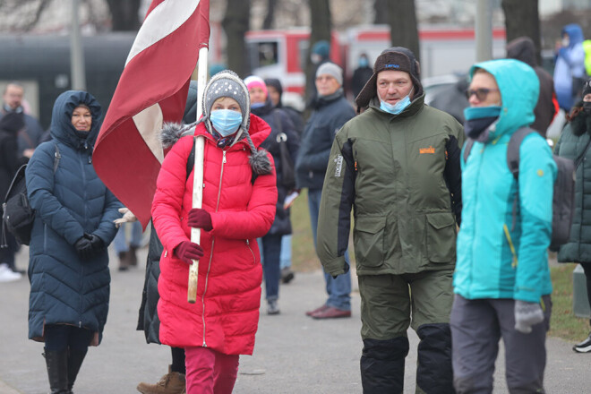 Sanākušie ir dažāda vecuma cilvēki, rokās dažiem ir Latvijas karogi.