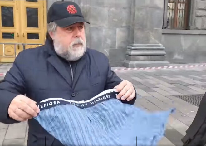 Manskis ar zilām apakšbiksēm pie FDD ēkas.