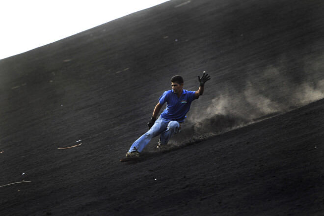 A tourist volcano surfs down the slopes of the Cerro Negro volcano, one of the most active in Nicaragua, in Leon, about 120 kilometers (75 miles) northwest from Managua July 23, 2012. REUTERS/Oswaldo Rivas (NICARAGUA - Tags: ENVIRONMENT SOCIETY TRAVEL SPORT)