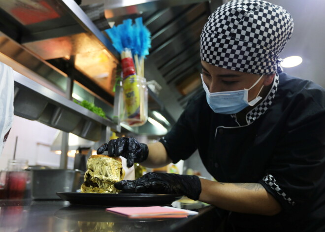 A cook covers a hamburger with gold foil at the Toro McCoy restaurant in Bogota, Colombia December 18, 2020. Picture taken December 18, 2020. REUTERS/Luisa Gonzalez