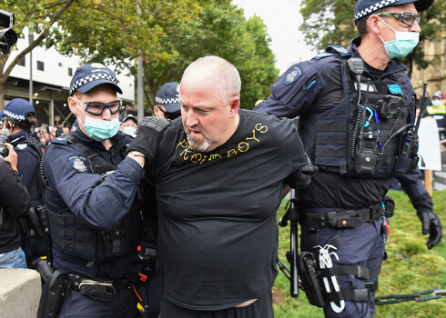 Policisti Melburnā aiztur vīrieti, kuram mugurā ir organizācijas "Proud Boys" krekliņš.