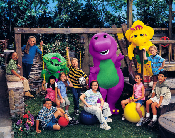 Demija (ar brillēm un sarkanu matu lentu) TV šovā “Barney and Friends”. Meitene uz dzeltenās bumbas ir Selēna Gomesa.