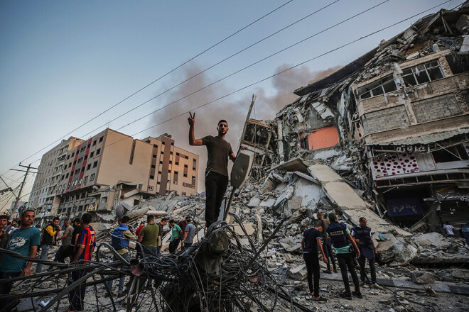 Palestīnieši pārmeklē Gazā sagrautās augstceltnes drupas.