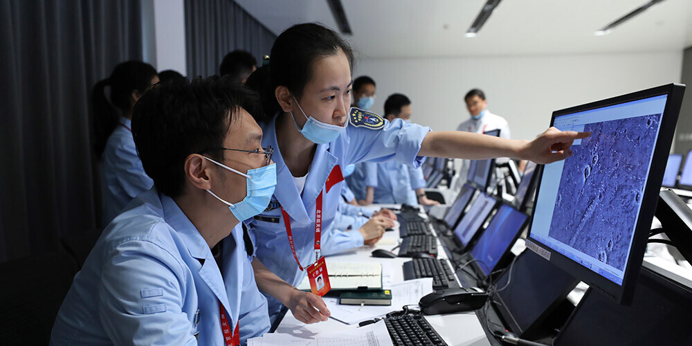 Ķīnas Nacionālās kosmosa pārvaldes tehniskie darbinieki vēro pašgājēja robota "Džužun" nolaišanās apkārtni.