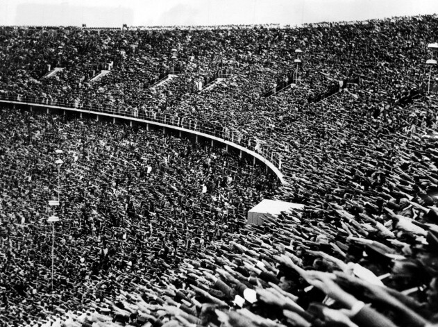 Vācieši salutē nacistu stilā, sveicot Ādolfu Hitleru, viņam ierodoties 1936. gada olimpisko spēļu atklāšanas ceremonijā Berlīnē. 