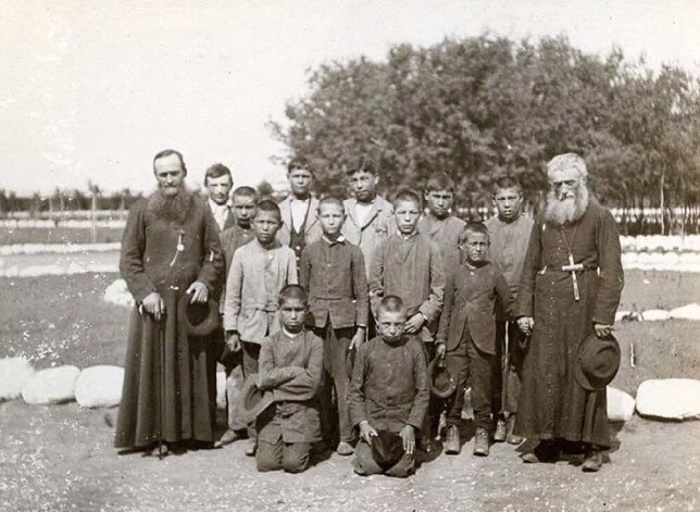 Vēsturisks foto no 1900.gada, kur redzami katoļu priesteri ar saviem internāta audzēkņiem.