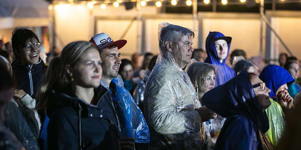 Jakās ar kapucēm un lietus plēvēs, cilvēki priecājas izbaudīt pilnvērtīga vasaras festivāla sajūtu.