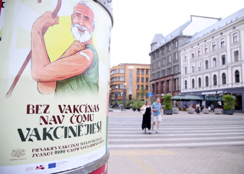 Vakcinācijas pret Covid-19 vides plakāts uz reklāmstaba.