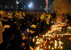 Cilvēki noliek svecītes Lāčplēša dienā pie Rīgas pils mūra 11.novembra krastmalā.