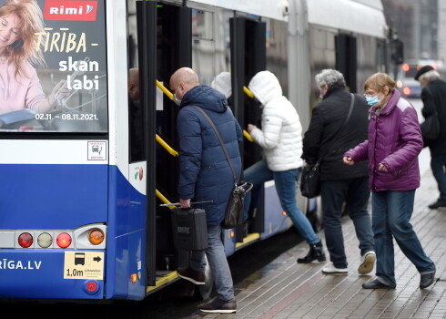 Cilvēki kāpj sabiedriskajā transportā.