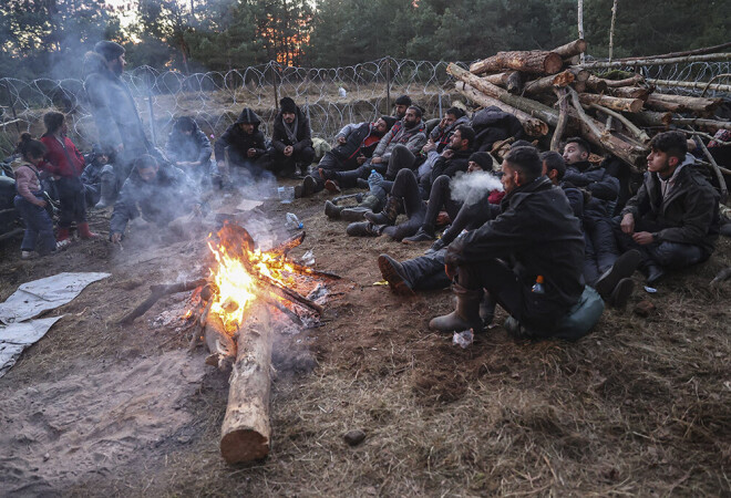 Migranti sildās pie ugunskura līdzās  Baltkrievijas-Polijas robežai.