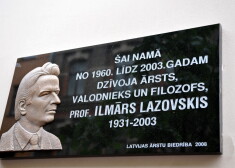 Plāksne ar cilni un uzrakstu "Šai namā no 1960.gada līdz 2003.gadam dzīvoja ārsts, valodnieks un filozofs, profesors Ilmārs Lazovskis (1931-2003)" pie nama Rīgā, Martas ielā 9.