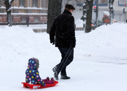 Vīrietis un bērns sniegputeņa laikā.