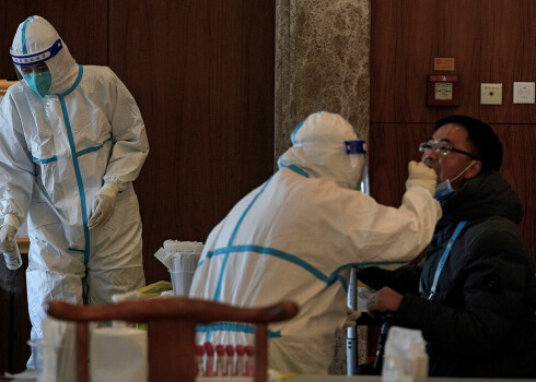 Mediķi vīrietim veic Covid-19 testu.