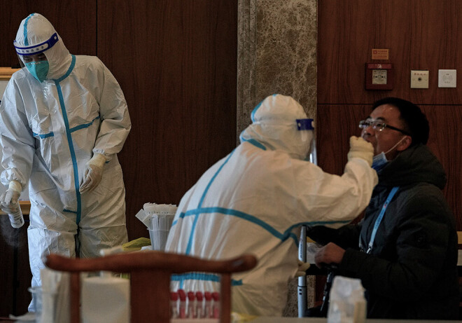 Mediķi vīrietim veic Covid-19 testu.