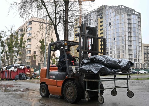 Vīrietis nogādā maisus ar civiliedzīvotāju līķiem Bučas morgā. 2022. gada 22. aprīlis.