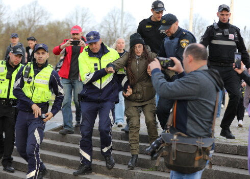 Valsts policijas darbinieki aiztur sievieti 10. maija vakarā pie pieminekļa Pārdaugavā, kur turpinās pulcēšanās un ziedu nolikšana.