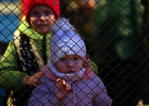 Trīs gadus vecā ukraiņu bēgļu meitene Karolina skatās caur žogu no vilciena perona Pžemsilas centrālajā dzelzceļa stacijā Polijā. Krievijas sāktā kara dēļ viņa bijusi spiesta pamest Ukrainu. 2022. gada 23. marts.