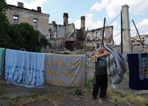 Vietējais iedzīvotājs Sergejs (65) izkar žāvēties veļu netālu no sagrautajām mājām Krievijas kara laikā Ukrainā. Luhanskas apgabala Lisičanska, 2022. gada 5. jūlijs. 