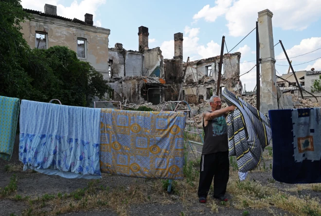 Vietējais iedzīvotājs Sergejs (65) izkar žāvēties veļu netālu no sagrautajām mājām Krievijas kara laikā Ukrainā. Luhanskas apgabala Lisičanska, 2022. gada 5. jūlijs. 