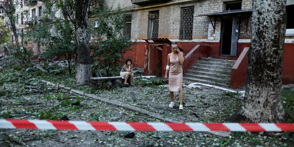 Ukrainiete Kramatorskā, Doņeckas apgabalā, 2022. gada 31. augustā, izmanto savu mobilo tālruni pie dzīvojamās ēkas, kas sabojāta pēc Krievijas trieciena, turpinoties Krievijas uzbrukumam Ukrainā