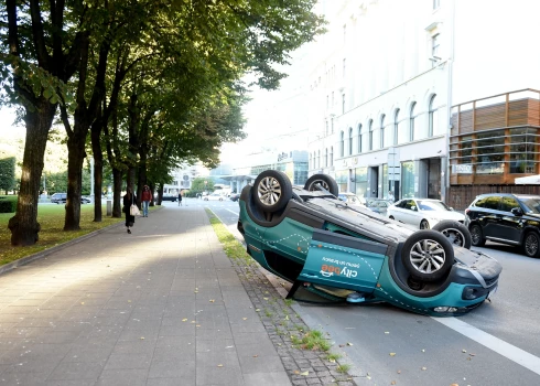 FOTO: Rīgas centrā uz jumta apgāzusies automašīna