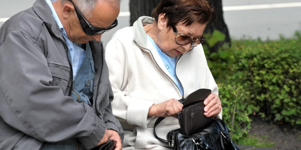 Cilvēki parkā uz soliņa.