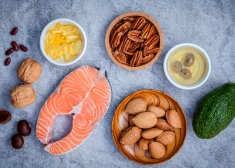 Atlasīti omega 3 un nepiesātināto tauku pārtikas avoti. Super ēdiens ar augstu omega 3 un nepiesātināto tauku saturu veselīgam pārtikai. Mandeles, pekanrieksti, lazdu rieksti, valrieksti, olīveļļa, zivju eļļa, lasis un avokado uz akmens fona.