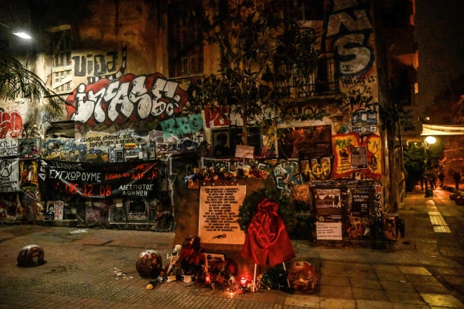 TOPSHOT - Candles are lit in front of a makeshift memorial for Alexis Grigoropoulos, killed by police, during a rally against police violence, marking the 14th anniversary of the 2008 fatal police shooting of a teenager in central Athens, on December 6, 2022. - Thousands of protesters demonstrated in Athens, Thessaloniki and other Greek cities against police violence, a day after a Roma youth was shot in the head in a police pursuit. The demonstrations were part of planned annual commemorations to mark the 2008 death of Alexandros Grigoropoulos, a 15-year-old fatally shot by police. (Photo by Louisa GOULIAMAKI / AFP)