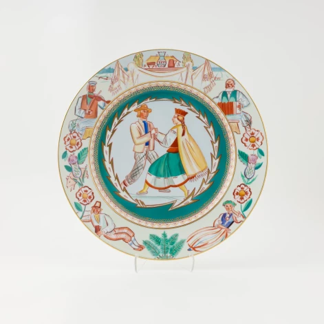 Dekoratīvs šķīvis “Tautas deja”. Romans Suta (apgleznojuma mets), Nadežda Boiko (Almazova) ? (apgleznojums), A/S "M. S. Kuzņecovs" Porcelāna, fajansa un māla izstrādājumu fabrika, 1937–1940. Foto: Māris Arbidāns.