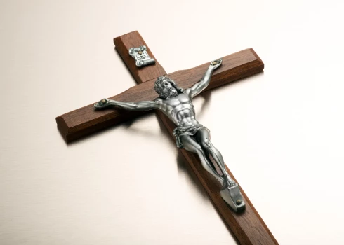 Sudraba metāla figūra ar krustā sisto Kristu uz koka krucifiksa.