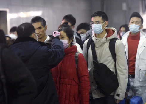 Workers use infrared thermometers to check the temperature of passengers arriving from Wuhan at a train station in Hangzhou in eastern China's Zhejiang Province, Thursday, Jan. 23, 2020. China closed off a city of more than 11 million people Thursday in an unprecedented effort to try to contain a deadly new viral illness that has sickened hundreds and spread to other cities and countries in the Lunar New Year travel rush. (Chinatopix via AP)