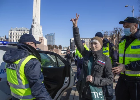 Valsts policijas darbinieki leģionāru gājiena laikā pie Brīvības pieminekļa aiztur sievieti, kuras apģērbu rotā pie krūtīm piešūts Krievijas karodziņš un kura pēdējās dienās kļuvusi populāra sociālajos tīklos, jo apmeklēja veikalu, nesot iepirkumu somu ar Krievijas armijas karā pret Ukrainu izmantoto simbolu "Z".