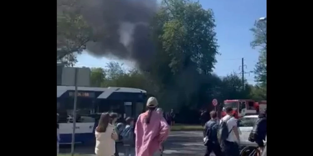 Cilvēki vēro ugunsdzēsēju darbu.