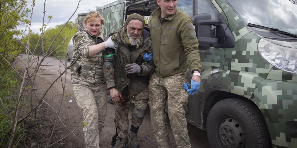 Military medics give first aid to a wounded soldier on the road near Bakhmut, Donetsk region, Ukraine, Thursday, May 11, 2023. (AP Photo/Boghdan Kutiepov)  XEL107