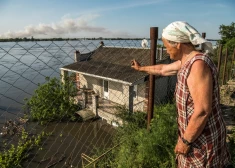 Vietējā iedzīvotāja skatās uz Dņepras upi, kas applūda pēc Nova Kahovkas dambja pārraušanas Krievijas uzbrukuma Ukrainai laikā, Hersonā, Ukrainā, 2023. gada 7. jūnijā.