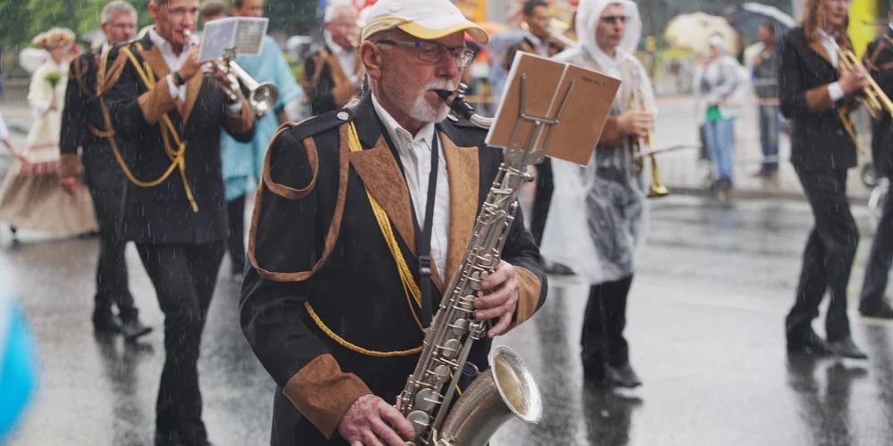 Dziesmu un deju svētku dalībnieki lietus laikā.
