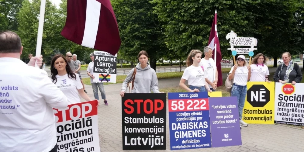 Протестующие принесли плакаты, призывающие спасать детей и остановить идеологию ЛГБТК+. (Фото: LETA)