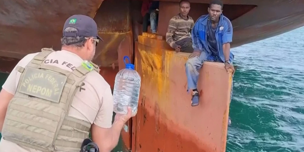 Brazīlijas krasta apsardzes darbinieks bēgļiem pasniedz ūdeni. 