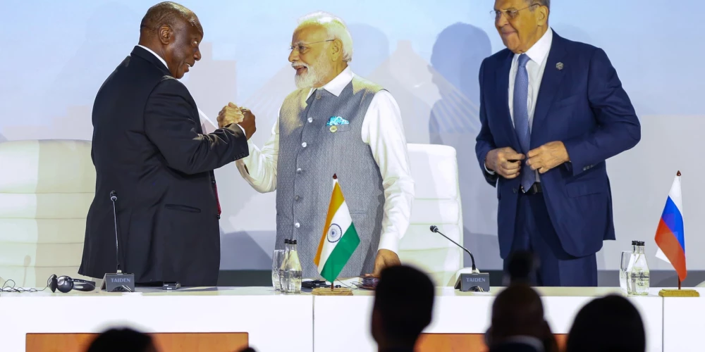 Dienvidāfrikas prezidents Kirils Ramafosa un Indijas premjerministrs Narendra Modi sadevušies rokās blakus Krievijas ārlietu ministram Sergejam Lavrovam BRICS līderu samitā.