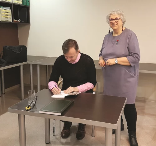 Dzejnieks Kārlis Vērdiņš raksta labus vārdus kādā no savām grāmatām pēc pasākuma Līvānu novada bibliotēkā.