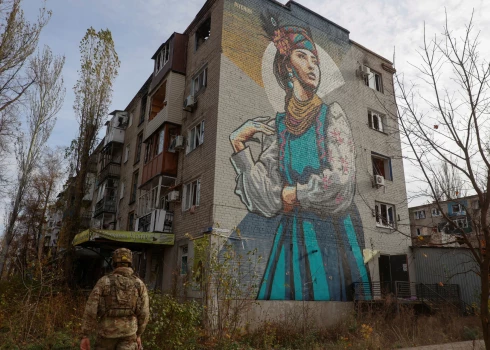 Ukraiņu aizstāvis pastaigājas blakus dzīvojamai ēkai, kas smagi bojāta pastāvīgos Krievijas militārajos uzlidojumos frontes līnijas pilsētiņā Avdīvkā Doneckas reģionā, 2023. gada 8. novembrī.