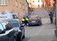 Policisti cenšas no auto izvilkt dzērājšoferi.