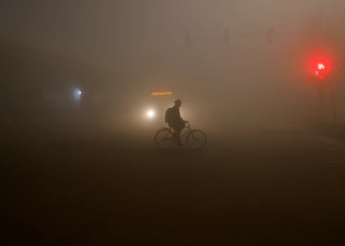 Vīrietis brauc ar velosipēdu Indijas galvaspilsētā Deli.