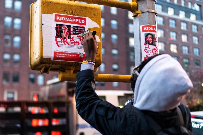 Attieksme skaidra – palestīniešu atbalstītājs ar krāsu nopūš “Hamas”  nolaupīto izraēliešu attēlus.