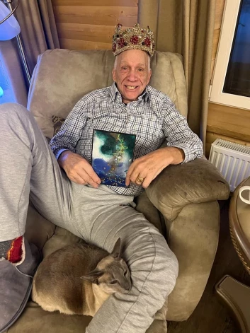 Jūlijs Krūmiņš ar Edītes Pauls-Vīgneres darināto Cēzara kroni galvā un kaķeni Džeinu klēpī.