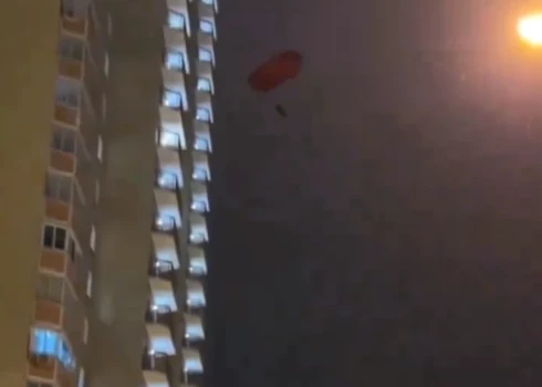 VIDEO: pārgalvis ar izpletni nolec no daudzstāvu dzīvojamās mājas balkona